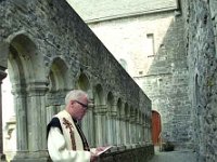 Don Colmcille O' Toole at Ballintubber Abbey, August 1994. - Lyons Ballintubber Abbey-118.jpg  Don Colmcille O' Toole (Thomas) a native of Ballintubber and Abbot of Cistercians in Roscrea reading from his breviary in the Cloisters, Ballintubber Abbey, August 1994. : 19940810 President Robinson opens Chapter House 4.tif, Ballintubber Abbey, Lyons collection