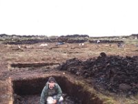 Archaeology student with the remains of a five thousand year old wall, Ceide Fields, 1989. - Lyons00-20692.jpg  "Roots that go down very deep"; story about Dr Caulfield archaeologist and the restoration project at the Ceide Fields, Keadue, North Mayo by Sonia Kelly. : 19890719 Ceide Fields Keadue County Mayo 1.tif, Ceide Fields, Farmers Journal, Lyons collection
