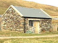 Clare Island.  Stone shed with a thatched house in the background. - Lyons0009218.jpg  Clare Island.  Stone shed with a thatched house in the background.