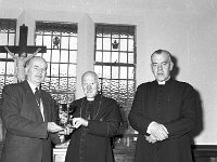 Michael Joe Gibbons at left presenting a new chalice from the Gibbons family, 1962. - Lyons0013833.jpg  Westport merchant Michael Joe Gibbons at left presenting a new chalice from the Gibbons family, Westport to Archbishop Joseph Walsh Archbishop of Tuam for use in celebration of mass in Croagh Patrick. At right Cannon Tom Cummins ADM Westport. 1962. : 1962 Presentation.tif, Lyons collection, Westport