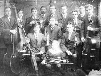 Old photo for Westport Town Hall booklet, 1973. - Lyons0013960.jpg  Old photos Liam Lyons copied for the Westport Town Hall Booklet 1903 - 1973. Westport's first dance band. Mascot Tommy Kelly (Jimmy Kelly seated). Front row from left: Arthur O' Malley (clarinet); Gerard Kelly (cornet); Francis Navin (clarinet).  Back row: William Navin (double base); William Edge; Robert McDermott (violin); J Mc Kennish; Henry swift; Robert Lang (violin); J McKennish; Henry swift; Robert Lang (violin); T Hewetson; Arthur Kidd; Edward Mayock (base fiddle). : 197304 Photo for Town Hall Booklet 5.tif, Lyons collection, Westport
