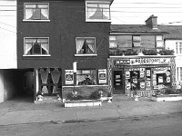 Chris and Mattie Reidy's shop and Guesthouse, Castlebar St.Westport, August 1980. - Lyons0015142.jpg  Chris and Mattie Reidy's shop and Guesthouse, Castlebar St.Westport, August 1980.  The white building at the left is part of the Castlecourt and the building on the right Mc Greals. : 19800826 Chris & Mattie Reidy's Shop.tif, Lyons collection, Westport