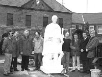 Placing the statue of St. Patrick on top of the pedestal on the Octagon, March 1990 - Lyons0015628.jpg  Placing the statue of St. Patrick on top of the pedestal on the Octagon, March 1990. Watching the preparations are members of the restoration committee. L-R : Joe Berry, Westport; Liam Walsh Chairman; Fr Tony King ADM Westport; Ken Thompson sculptor; John Coffey Monumental Works; Tom Durcan; Cathal Hughes and Sean Staunton, Restoration Committee. : 19900307 Placing of the Statue of St Patrick 11.tif, Lyons collection, Westport